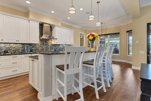 kitchen with dark hardwood / wood-style flooring, white cabinetry, wall chimney exhaust hood, and decorative backsplash