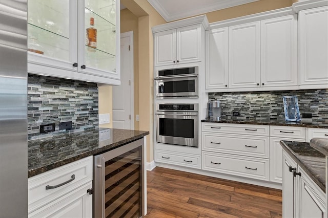 kitchen with white cabinetry, stainless steel appliances, dark stone countertops, tasteful backsplash, and beverage cooler