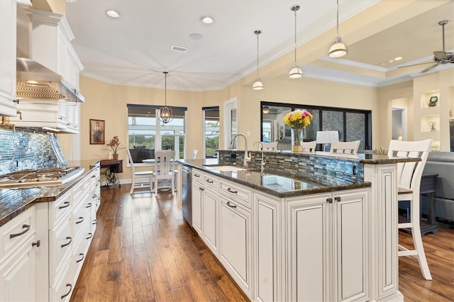 kitchen featuring wall chimney exhaust hood, an island with sink, dark hardwood / wood-style flooring, and sink