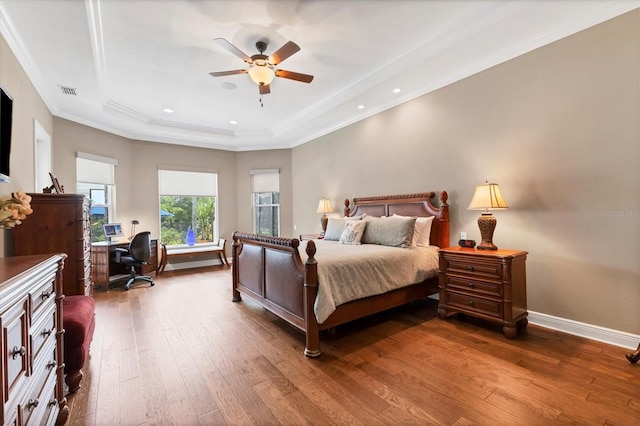 bedroom featuring ceiling fan, wood-type flooring, a raised ceiling, and ornamental molding