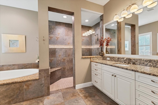 bathroom featuring tiled bath, vanity, and tile patterned flooring