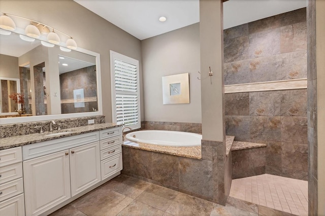 bathroom with tile patterned floors, a relaxing tiled tub, and vanity