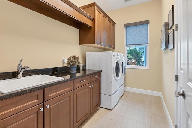 washroom featuring light tile patterned flooring, sink, cabinets, and washer and clothes dryer