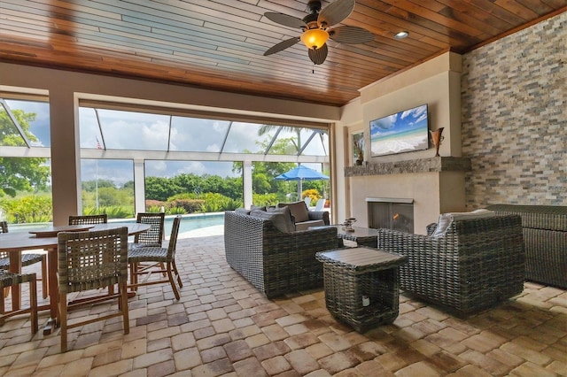 sunroom / solarium featuring exterior fireplace, wood ceiling, and a healthy amount of sunlight