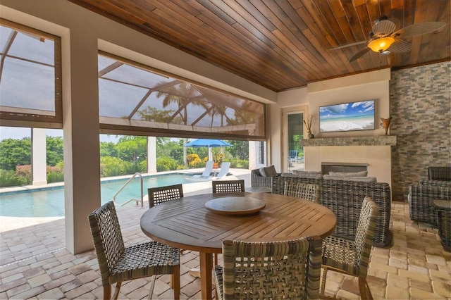 sunroom with a fireplace, wood ceiling, and ceiling fan