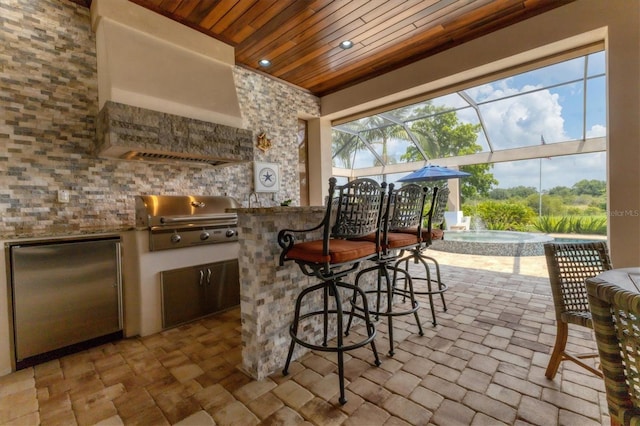 view of patio with a lanai, area for grilling, an outdoor kitchen, and exterior bar