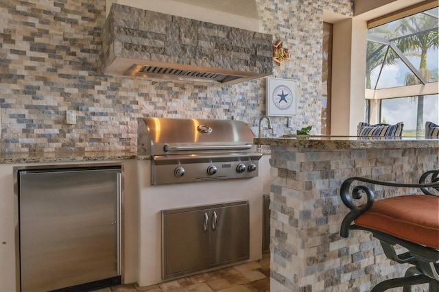 view of patio / terrace featuring glass enclosure, an outdoor kitchen, and area for grilling