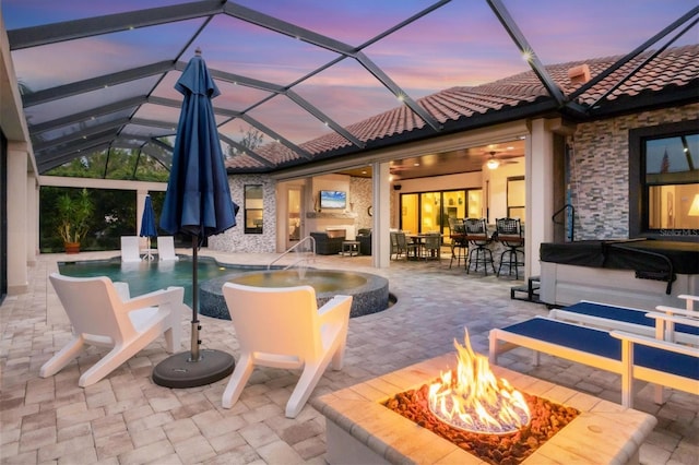 exterior space with ceiling fan, a patio, glass enclosure, and a fire pit