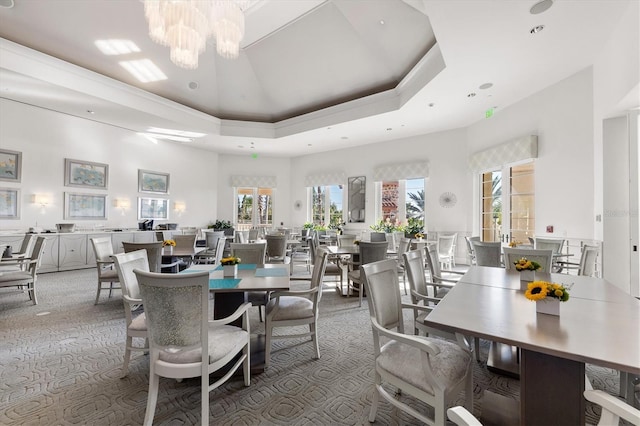 carpeted dining room featuring french doors, a raised ceiling, a chandelier, and a high ceiling