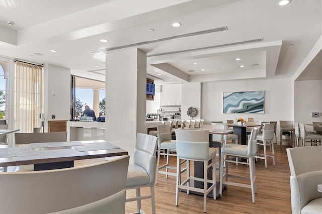 dining area featuring a tray ceiling, plenty of natural light, and light hardwood / wood-style floors