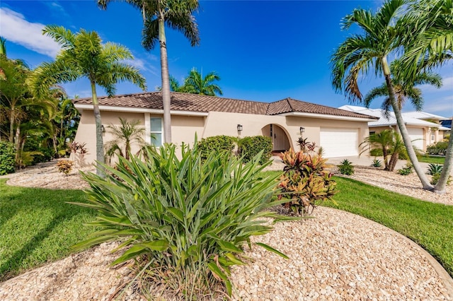 mediterranean / spanish house featuring a front yard, a tile roof, an attached garage, and stucco siding