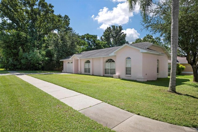 ranch-style home with a garage and a front lawn