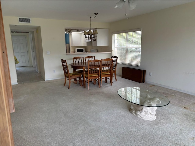 dining room featuring light carpet and ceiling fan with notable chandelier