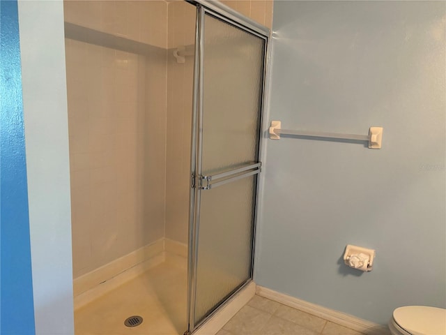 bathroom featuring tile patterned flooring, toilet, and an enclosed shower