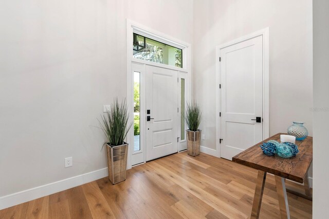 foyer entrance with light hardwood / wood-style floors and a high ceiling