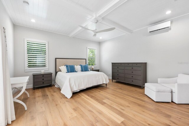 bedroom featuring beam ceiling, a wall mounted AC, light hardwood / wood-style flooring, and ceiling fan