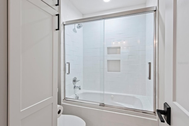 bathroom featuring toilet and combined bath / shower with glass door