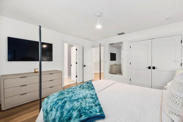 bedroom featuring a closet, ensuite bath, and light wood-type flooring