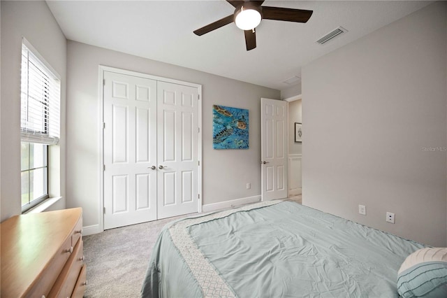 bedroom with light carpet, multiple windows, a closet, and ceiling fan