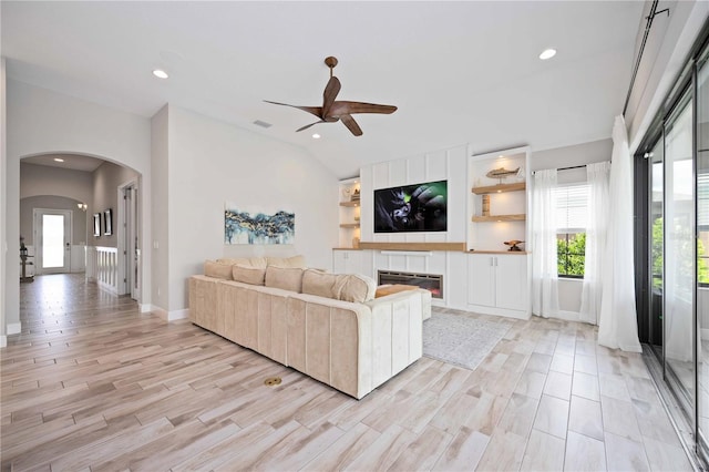 living room with a healthy amount of sunlight, lofted ceiling, and light wood-type flooring