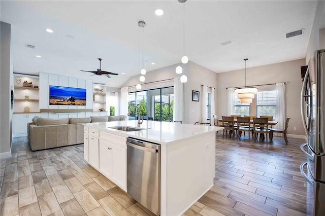 kitchen with white cabinetry, an island with sink, stainless steel appliances, decorative light fixtures, and sink