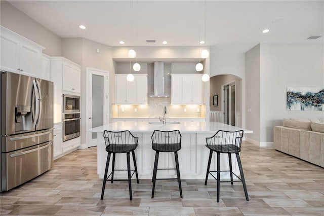 kitchen featuring a center island with sink, hanging light fixtures, appliances with stainless steel finishes, and white cabinets