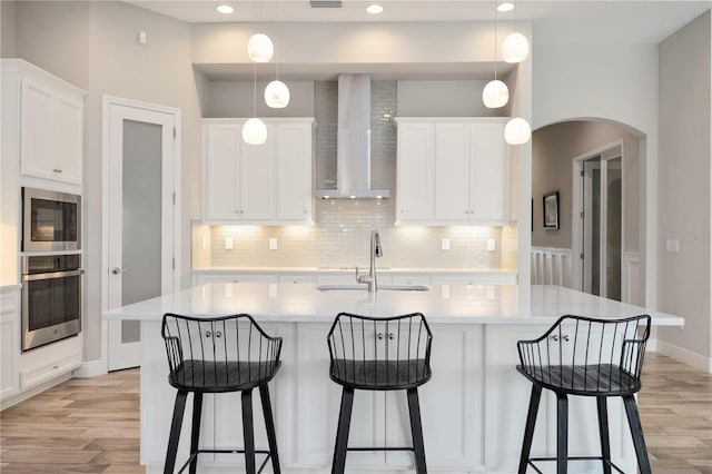 kitchen featuring wall chimney range hood, hanging light fixtures, oven, and built in microwave