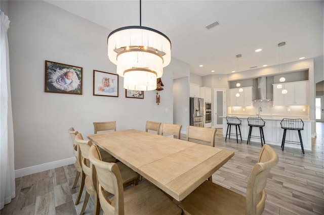 dining area featuring sink, light wood-type flooring, and a chandelier