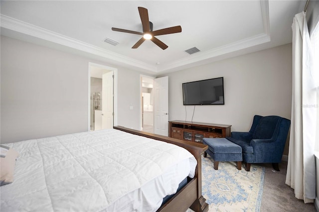 bedroom featuring a tray ceiling, carpet flooring, ensuite bathroom, ceiling fan, and ornamental molding