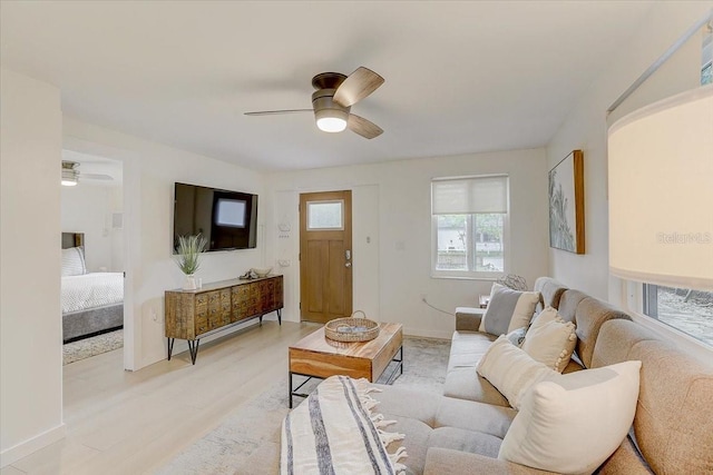 living room with a ceiling fan, baseboards, and light wood finished floors