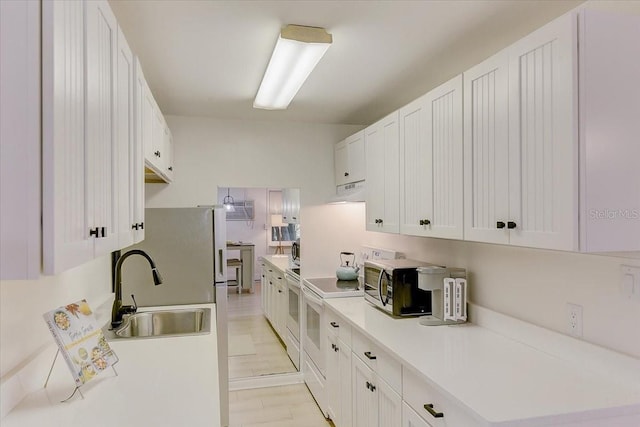 kitchen with white electric range oven, white cabinets, a sink, and light countertops