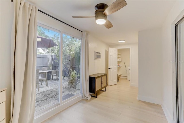 hall with a wall unit AC, baseboards, and light wood finished floors