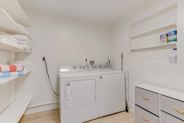 laundry area featuring baseboards, light wood-style flooring, laundry area, and washer and dryer