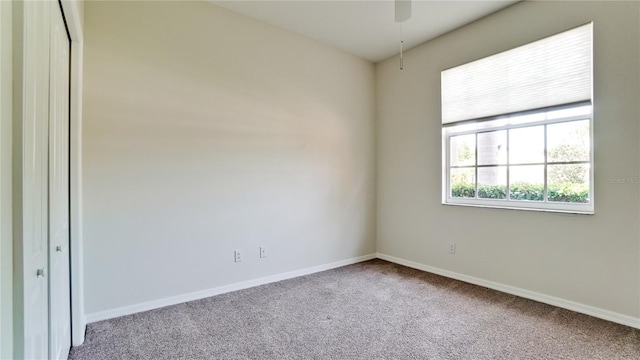 carpeted spare room featuring ceiling fan