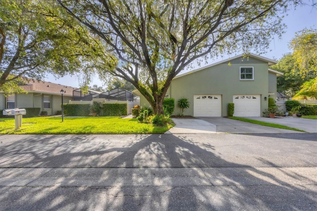 view of front of property featuring a garage, a front yard, and glass enclosure