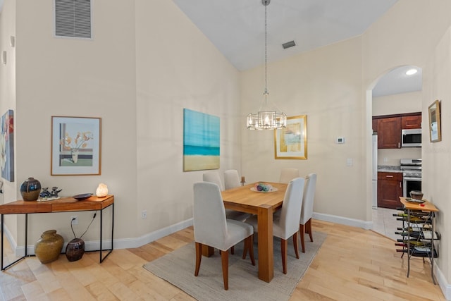 dining area with light wood-style floors, arched walkways, visible vents, and baseboards