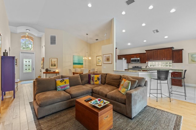 living room with wood finished floors, visible vents, and an inviting chandelier