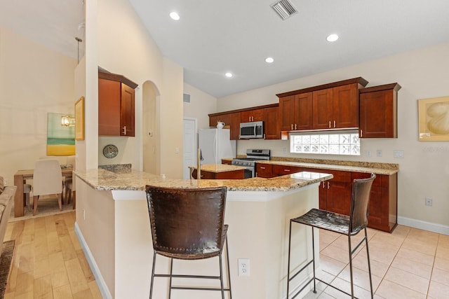 kitchen with stainless steel appliances, visible vents, light stone countertops, a peninsula, and a kitchen breakfast bar