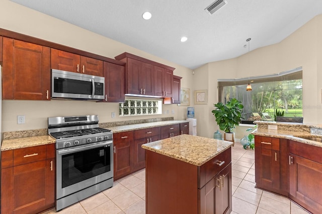 kitchen featuring stainless steel appliances, visible vents, decorative light fixtures, and light stone counters