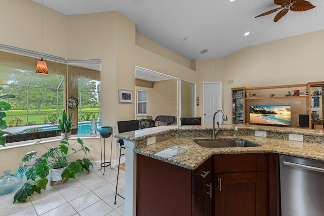 kitchen featuring lofted ceiling, light stone counters, a sink, stainless steel dishwasher, and light tile patterned flooring