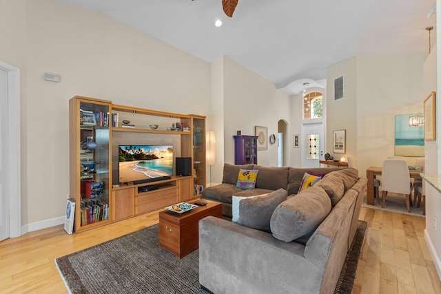 living area featuring arched walkways, visible vents, light wood-style flooring, and baseboards