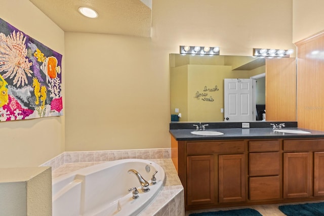 bathroom with a garden tub, a sink, a textured ceiling, and double vanity