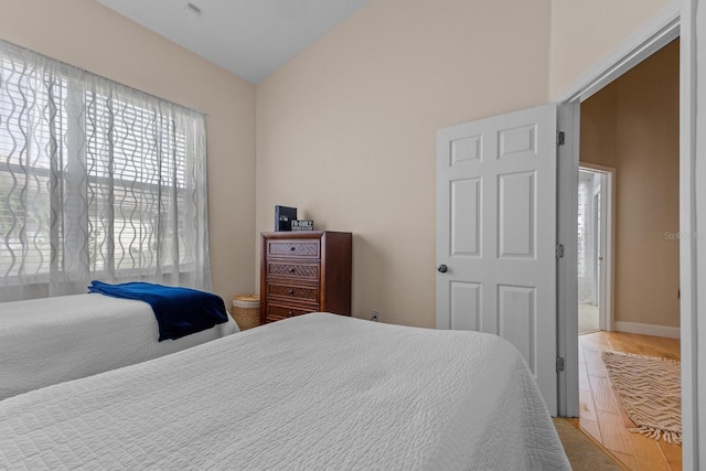 bedroom with lofted ceiling and baseboards