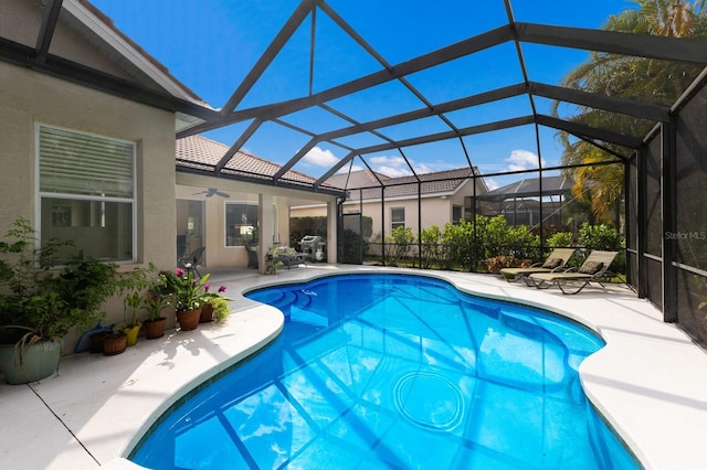 pool featuring glass enclosure, a patio area, and a ceiling fan