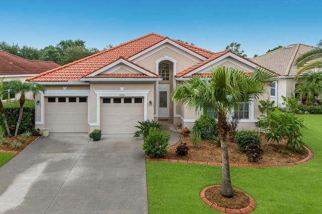 mediterranean / spanish house featuring an attached garage, driveway, a front yard, and a tiled roof