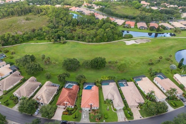 drone / aerial view featuring view of golf course, a water view, and a residential view