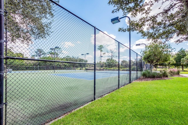 view of sport court featuring a yard and fence