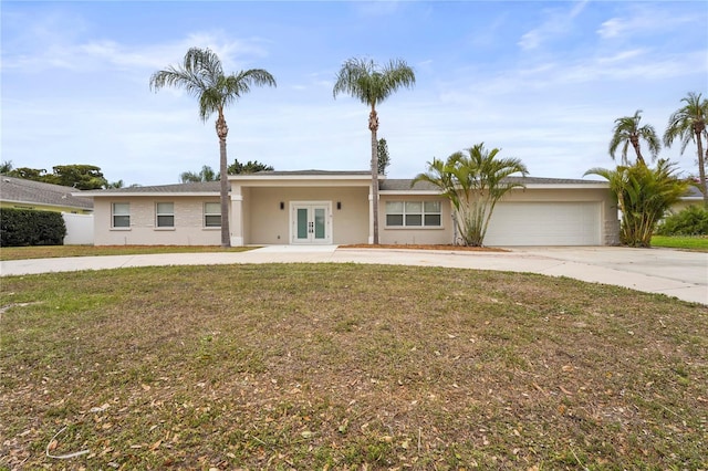 ranch-style home with an attached garage, driveway, french doors, and stucco siding