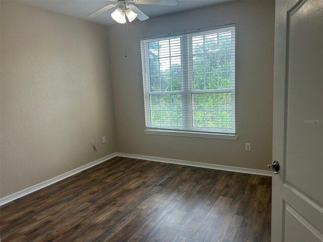 empty room with ceiling fan, dark hardwood / wood-style floors, and plenty of natural light