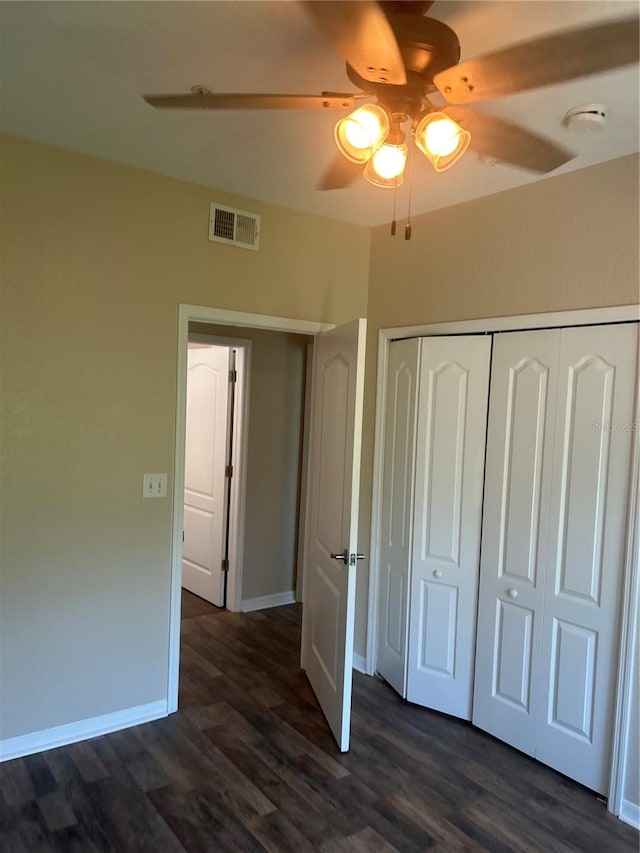 unfurnished bedroom with a closet, dark wood-type flooring, and ceiling fan